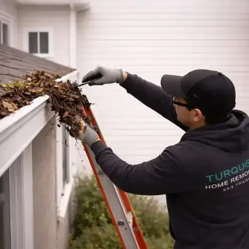 Contractor cleaning roof gutter and removing debris during home maintenance in Lake Street San Francisco